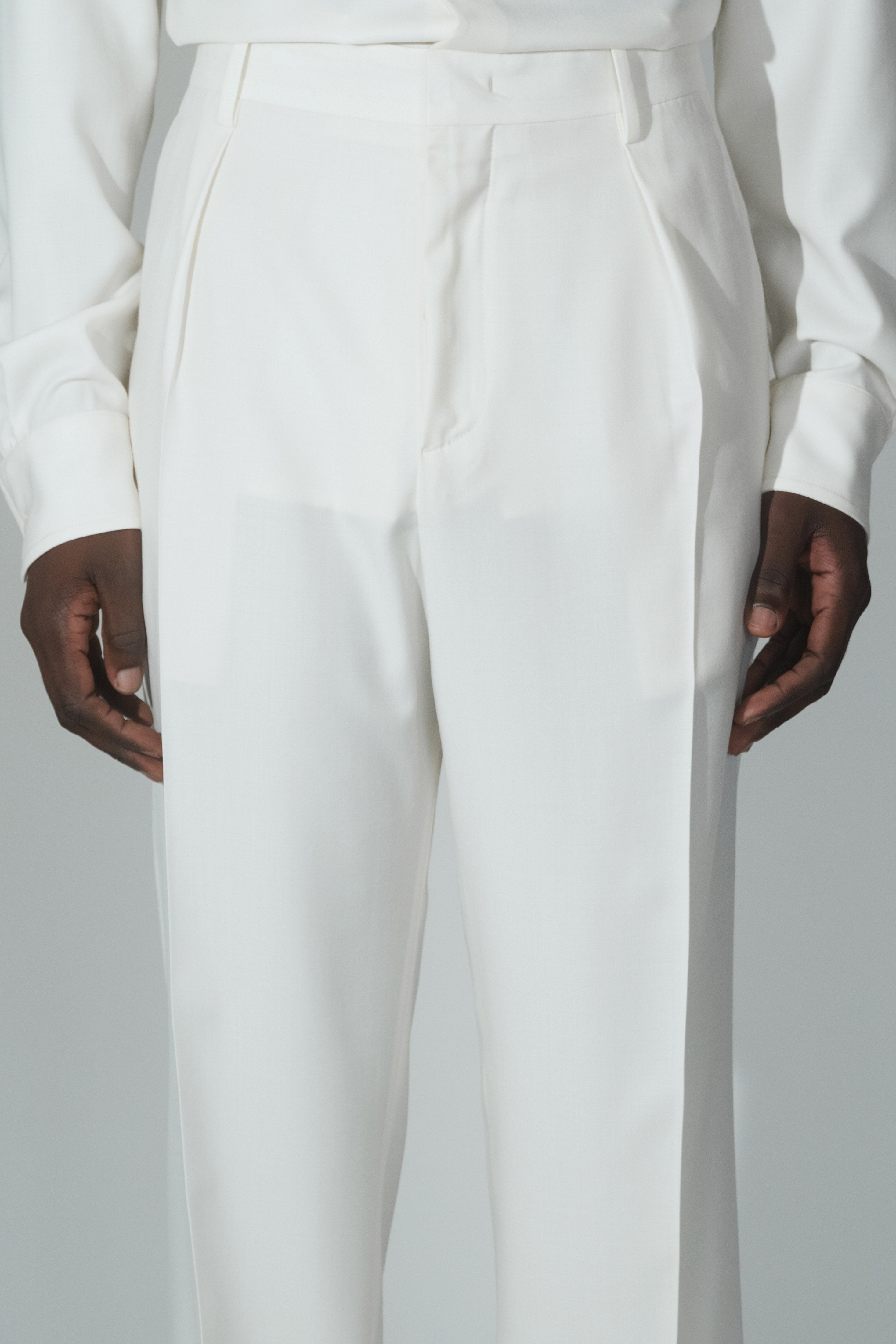 Close-up of RÆR STUDIOS x Kevin Lutolf pleated trousers in off-white