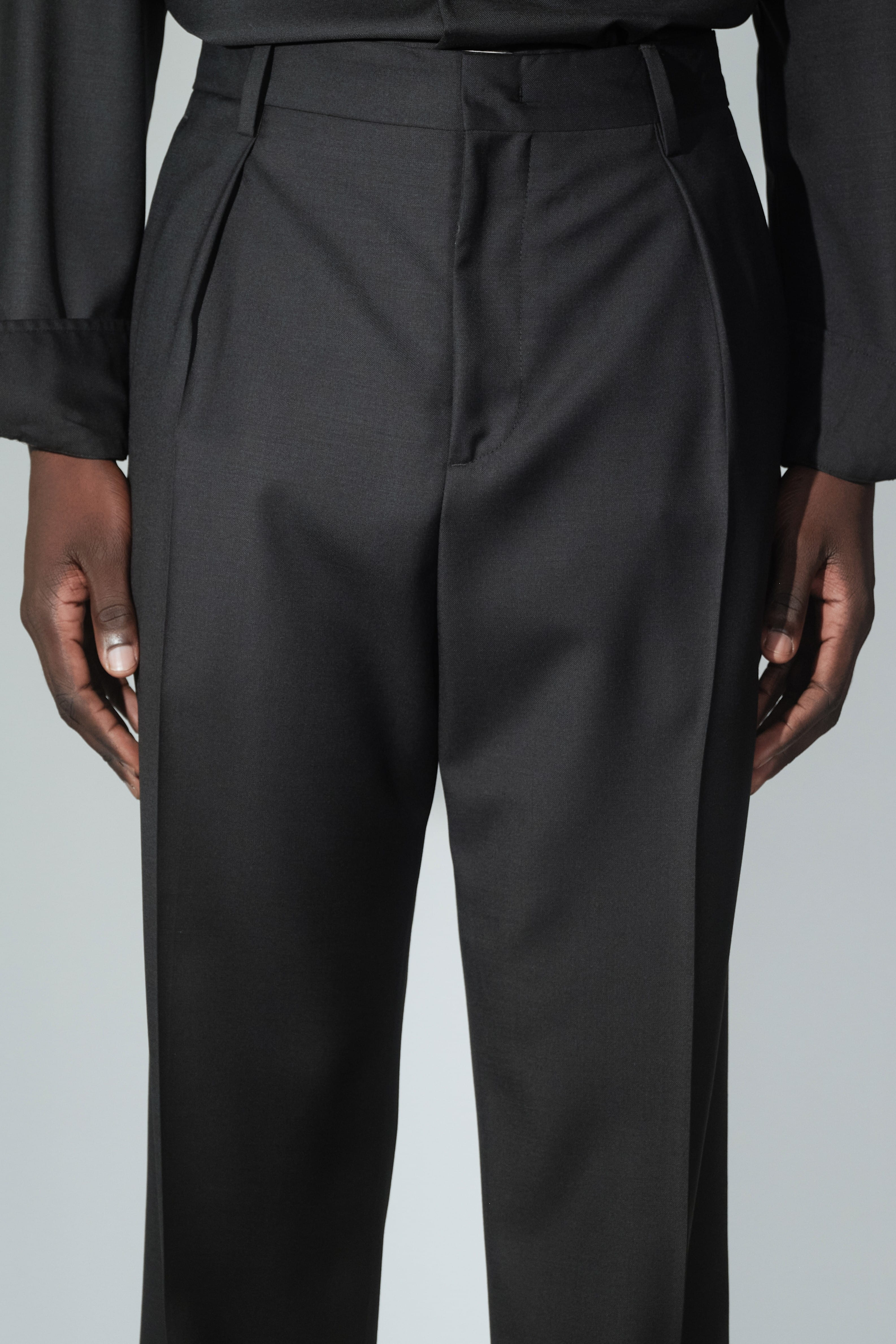 Close-up of RÆR STUDIOS x Kevin Lutolf pleated trousers in black