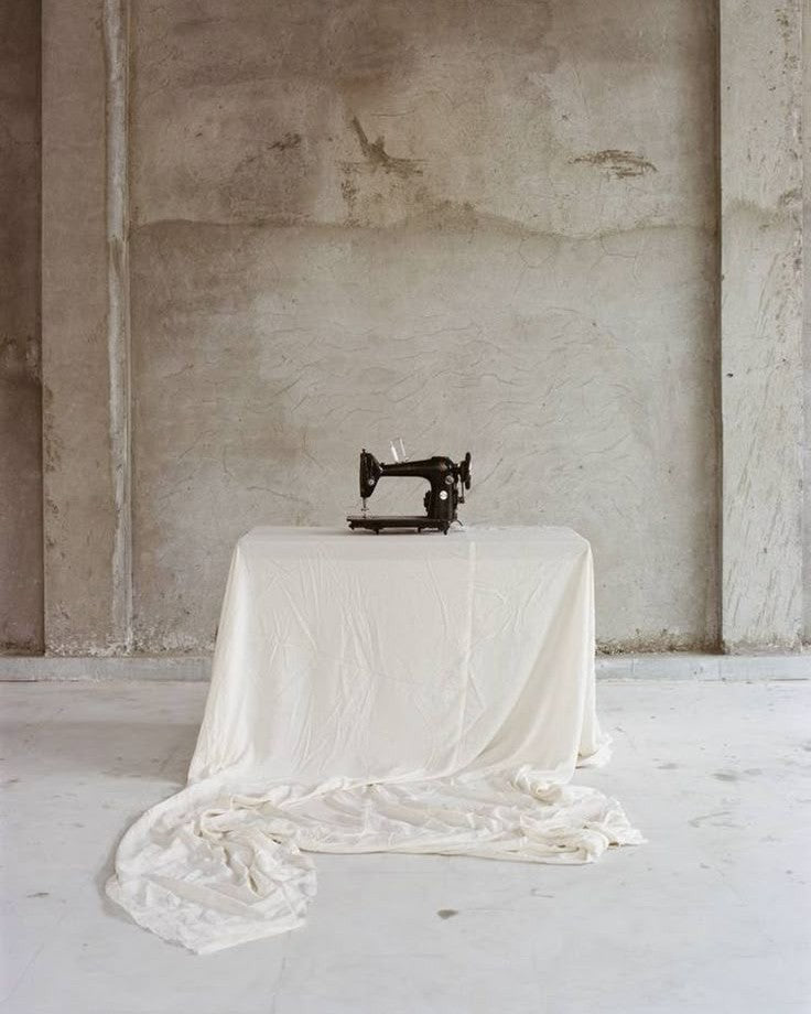 RÆR | RAER Vintage sewing machine on a draped white cloth table against a textured concrete wall